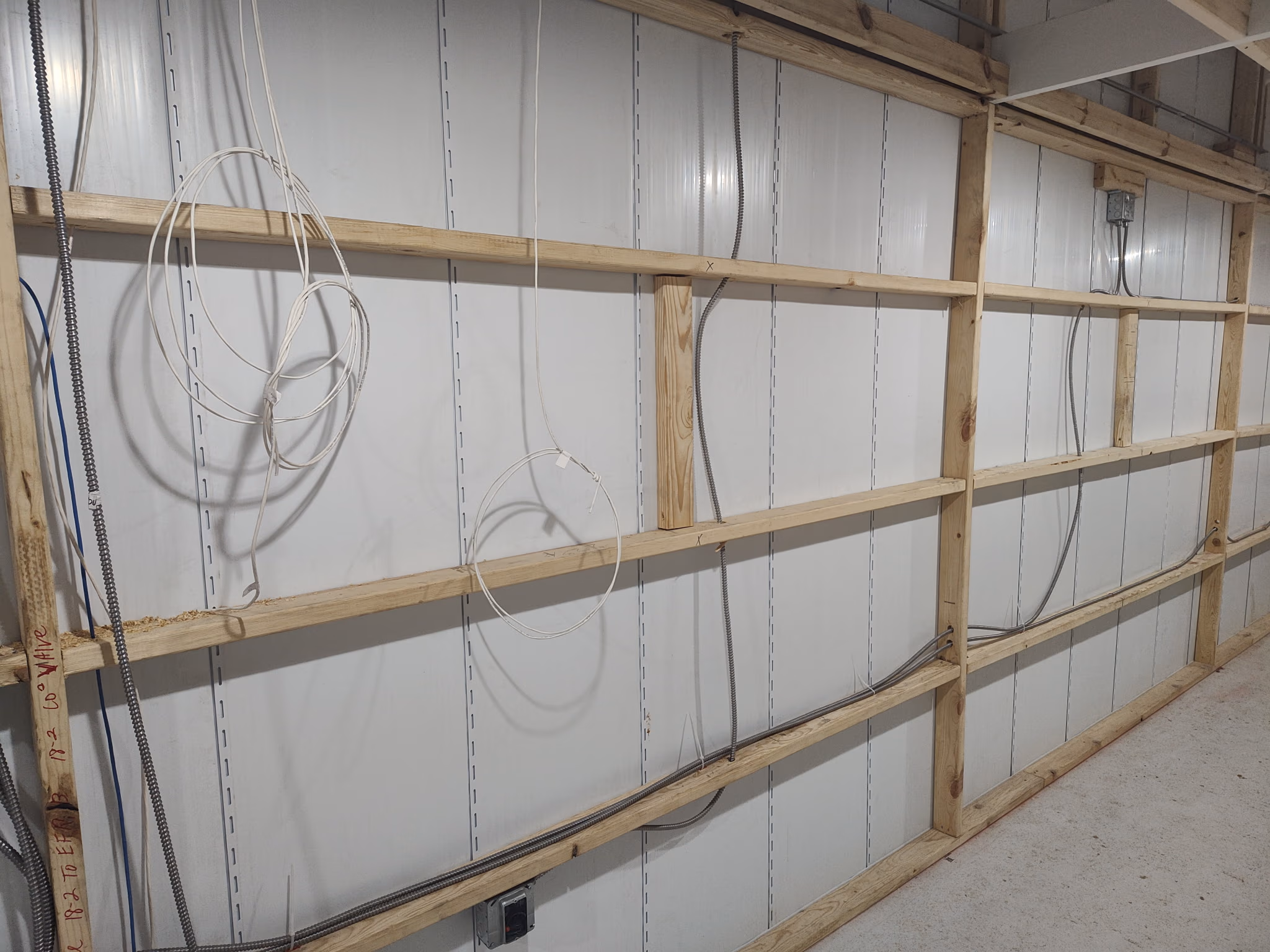 Interior wall frame with electrical conduit and wiring in unfinished construction area.