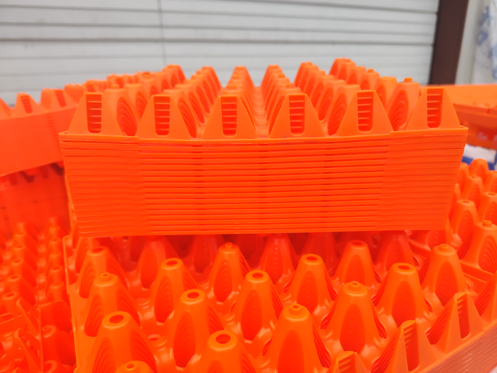 Stacks of bright orange plastic trays with cone-shaped compartments, used for holding eggs.